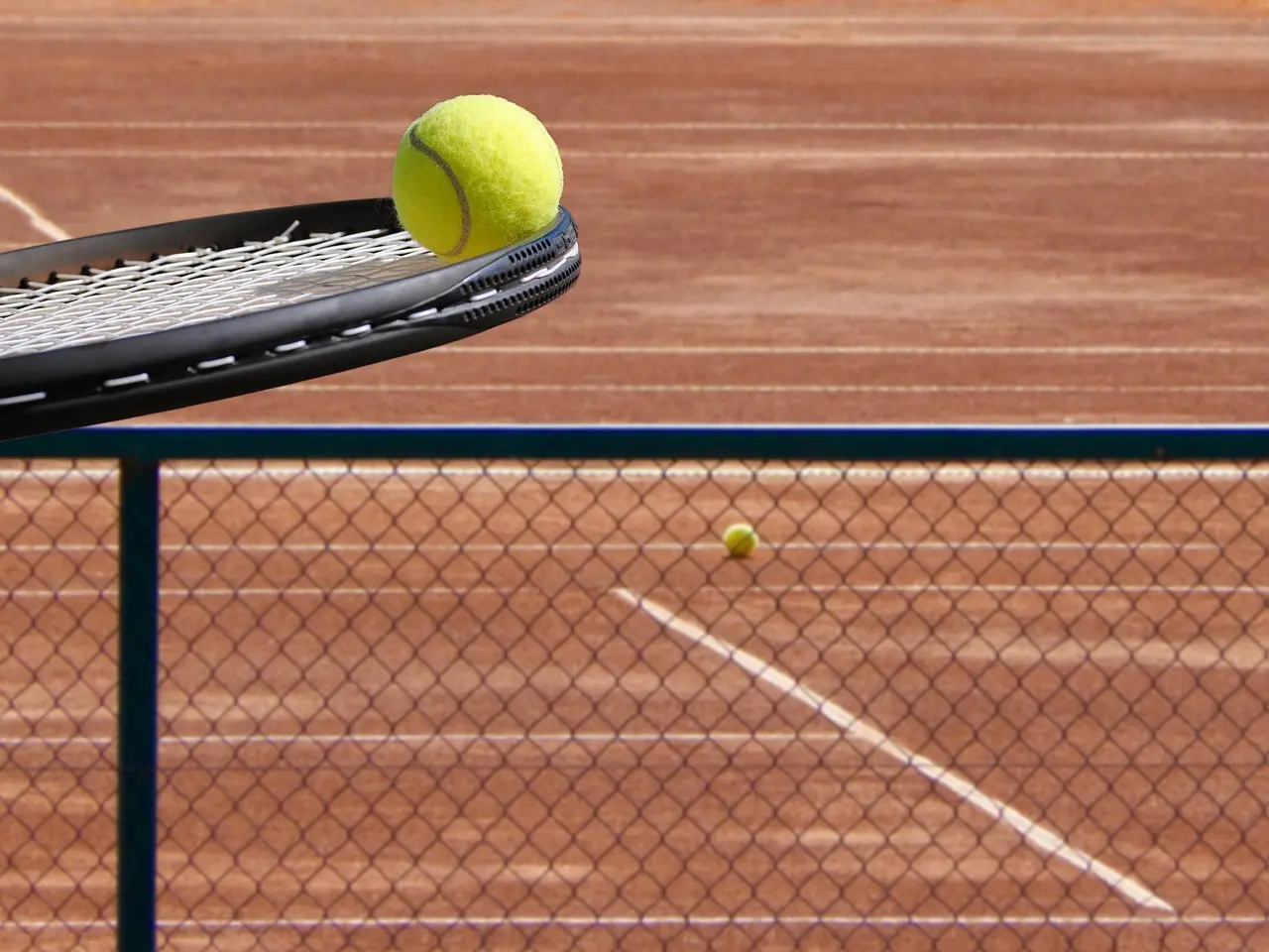Tennisketsjer med tennisbold over en grusbane