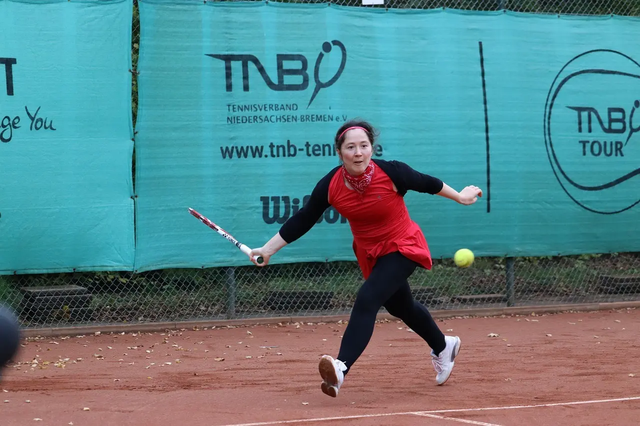 Tennisspiller der returnerer et slag på en grusbane