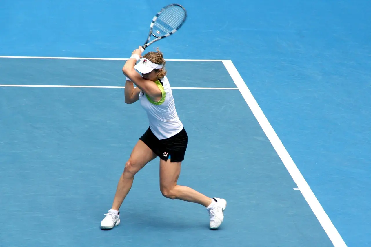 Tennisspiller der slår en backhand på en blå tennisbane